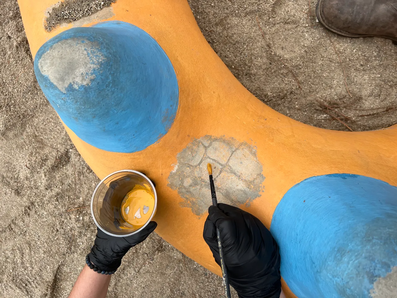 Jennifer painting fine colorful details on a concrete dragon sculpture