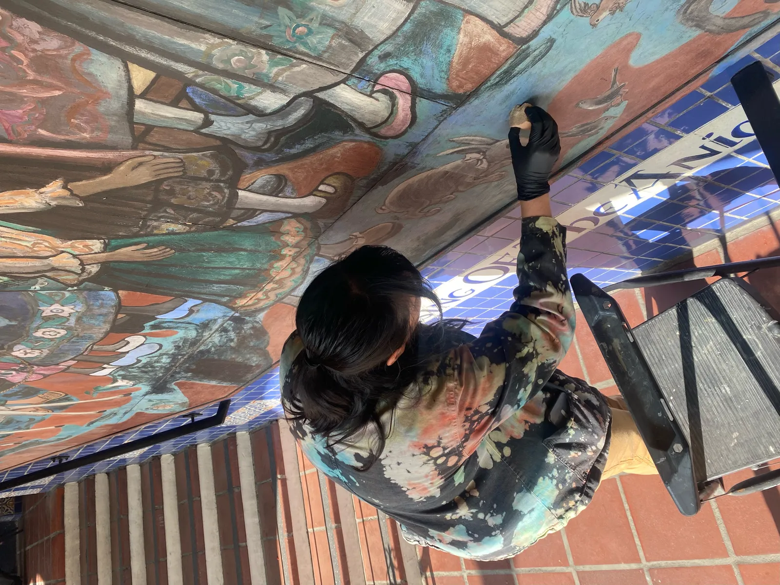 jennifer payan standing in front of the Blessing of the animals mural