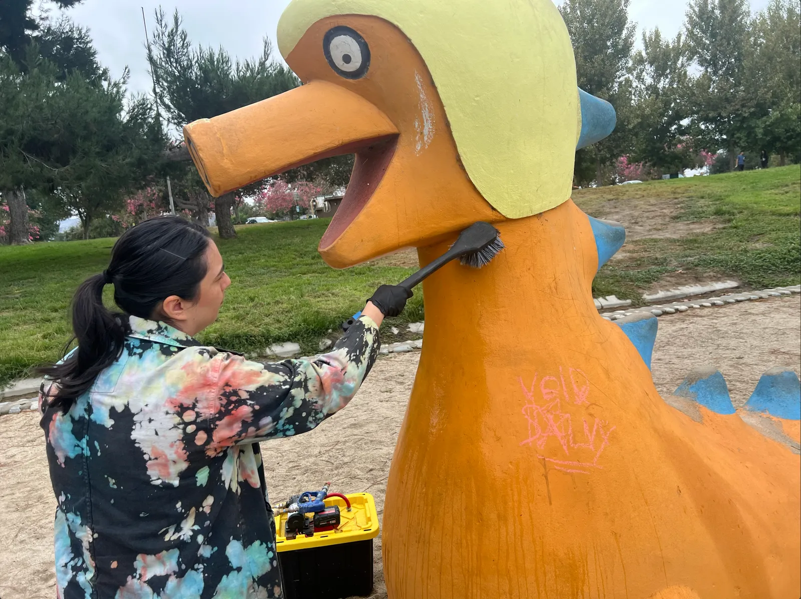 Jennifer using a soft-bristled brush to clean concrete sculpture surfaces