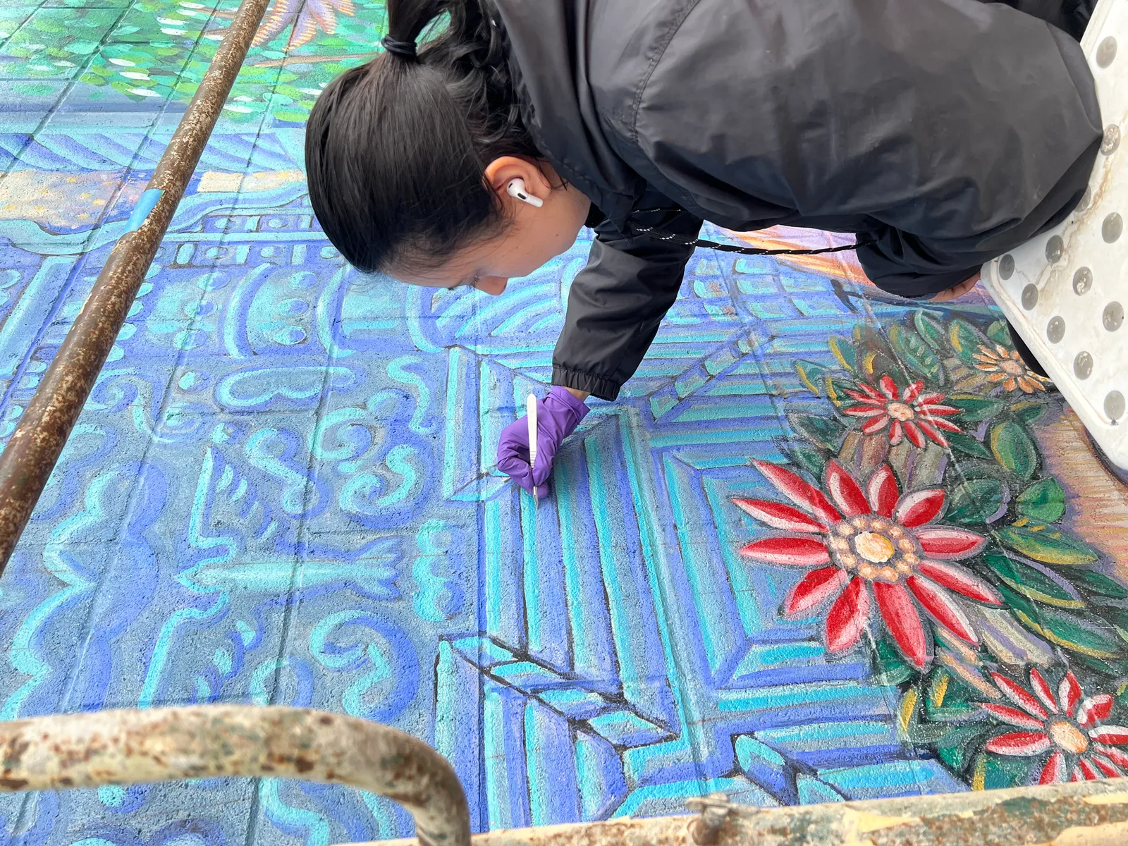 Jennifer removing surface dirt from the mural surface using conservation sponges